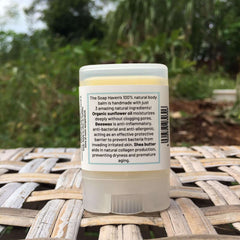 A travel-size twist-up tube of The Soap Haven Unscented Body Balm showing the back label with the 3 natural ingredients and benefits.
